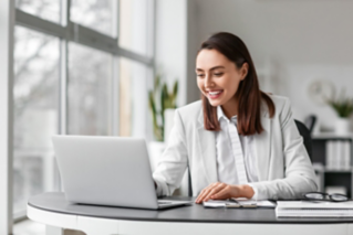 Pretty businesswoman working with laptop at table in office